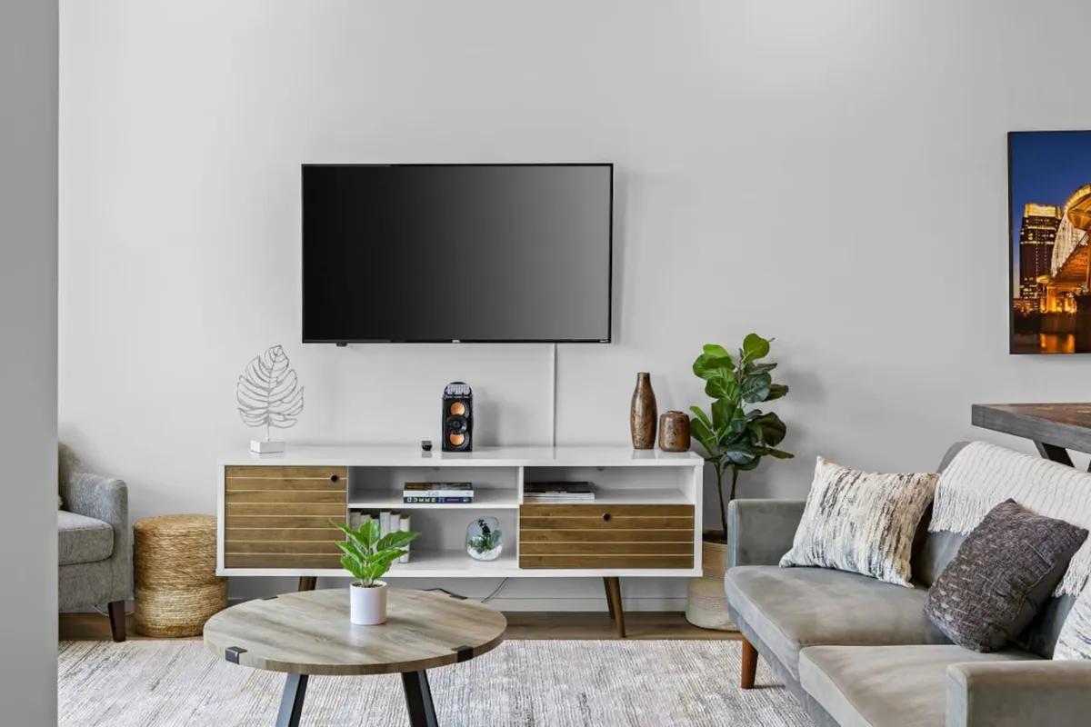 A welcoming living area with a comfortable sofa, coffee table, television, and decorative plants. The space is designed for casual relaxation, reading, or intimate socializing, providing a sense of home away from home. The setup is conducive to winding down after a day of meetings or exploring the city.