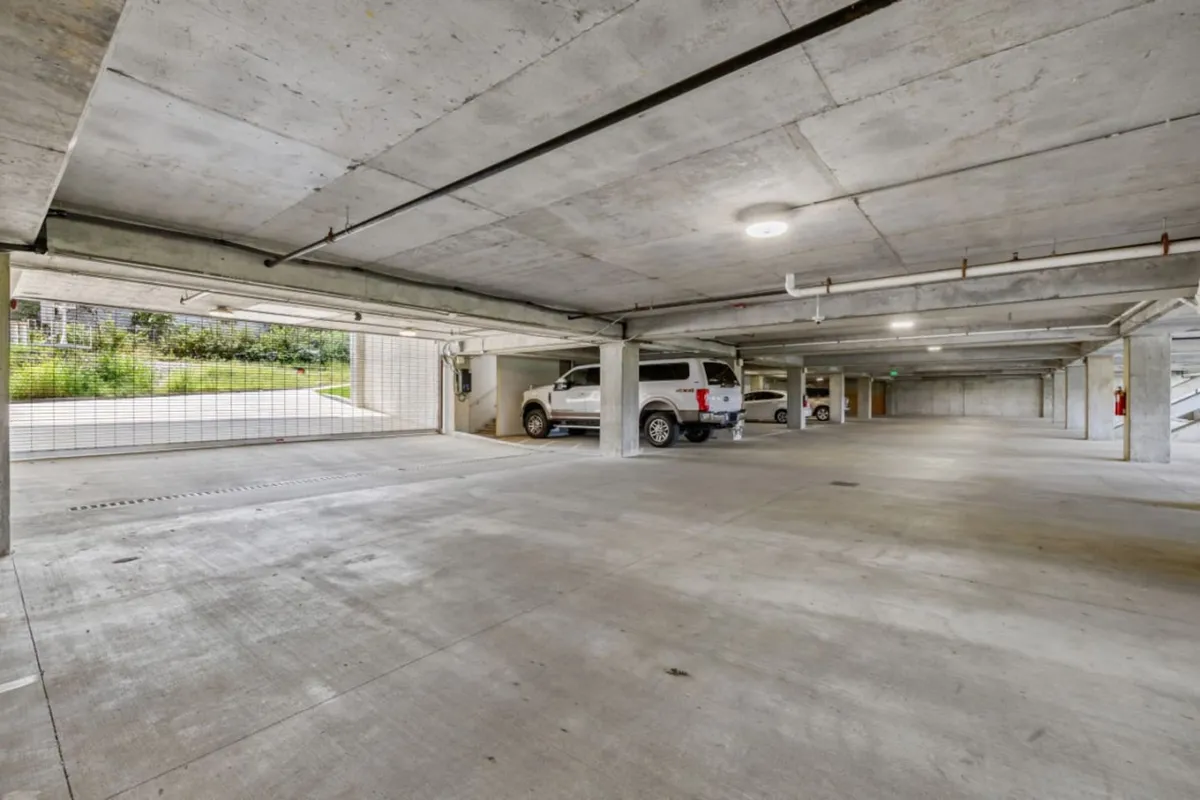 This image captures the private, gated garage area, showing several parked vehicles in a well-lit, concrete parking structure. The setting highlights the convenience and security of on-site parking, with clear access points and ample space for arrivals and departures.